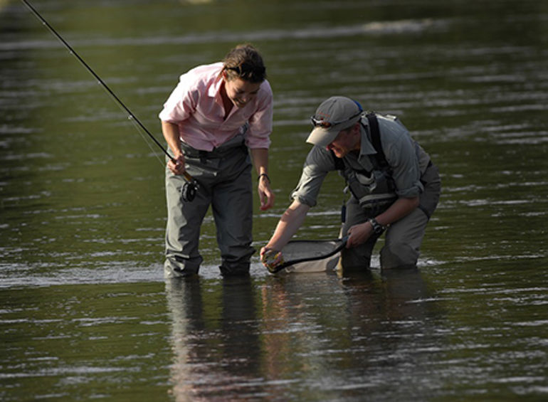 Two fishermen catching a fish in a river Two fishermen catching a fish in a river