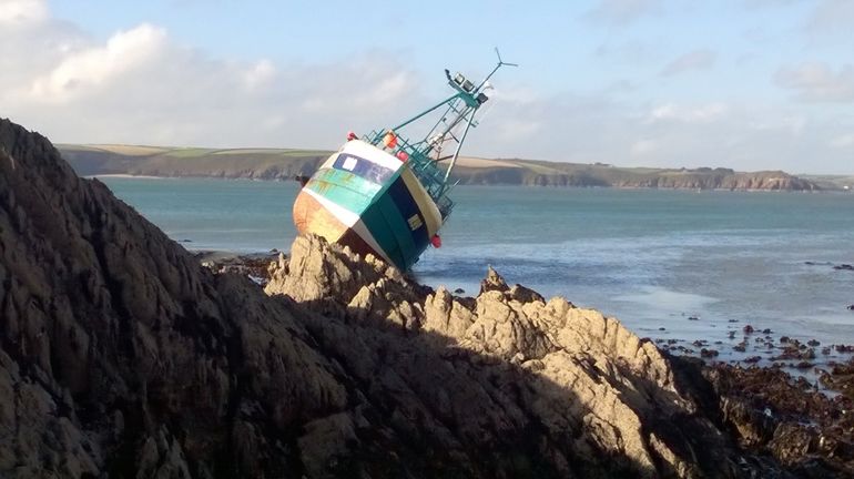A small fishing boat stranded on some rocks A small fishing boat stranded on some rocks