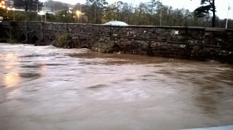 Fast flowing high river against an old brick bridge Fast flowing high river against an old brick bridge