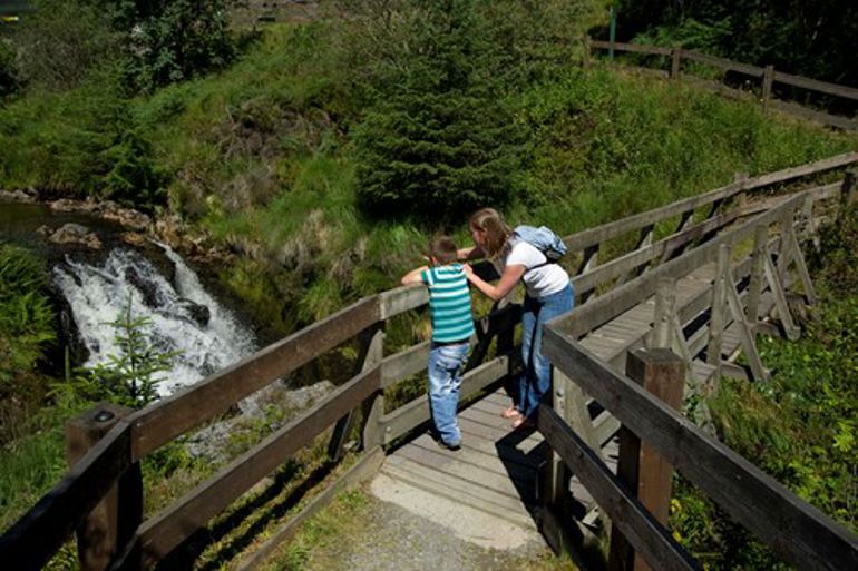 Mother and child watching the waterfall from a bridge Mother and child watching the waterfall from a bridge