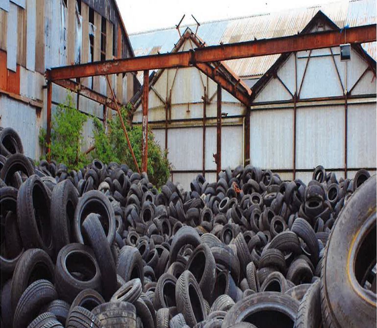 Lots of car tyres piled up outside a warehouse Lots of car tyres piled up outside a warehouse