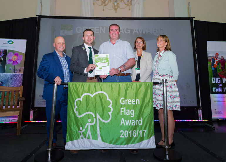 a group of 5 people standing behind a green flag awards 2016-17 banner a group of 5 people standing behind a green flag awards 2016-17 banner