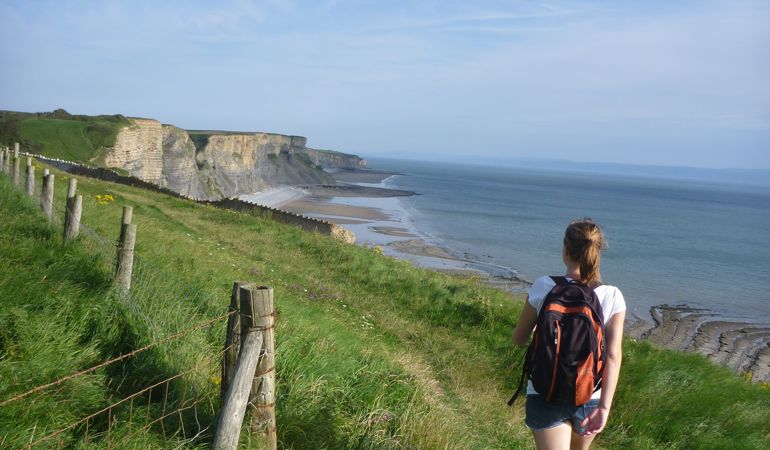 Woman walking along a coastal path Woman walking along a coastal path