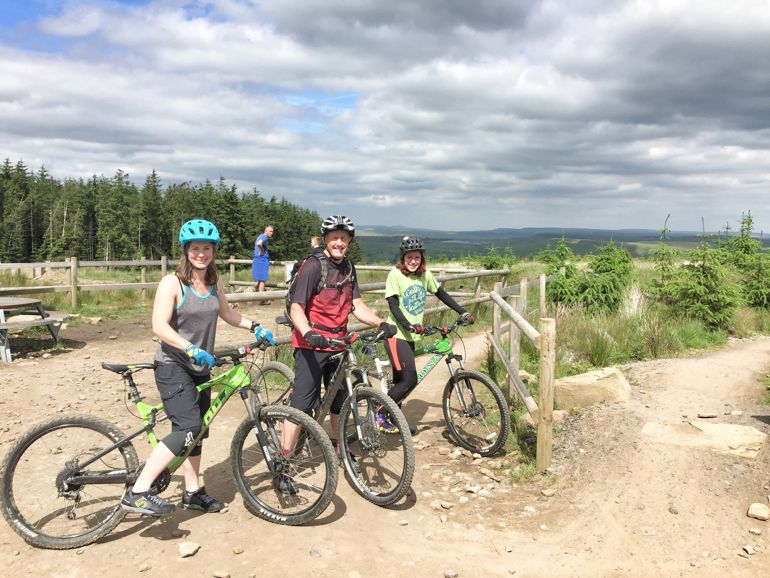 Three people on a bike trail standing with their bikes Three people on a bike trail standing with their bikes