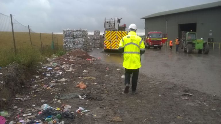 NRW officer at the landfill site with fire engine and waste in the background NRW officer at the landfill site with fire engine and waste in the background