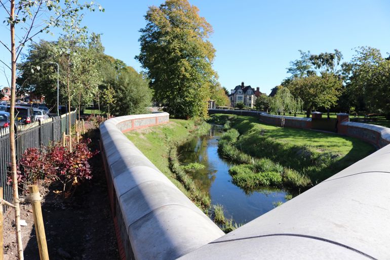 Photo of the green banks of the Roath Brook with new flood walls with grey coping stones running alongside the banks Photo of the green banks of the Roath Brook with new flood walls with grey coping stones running alongside the banks