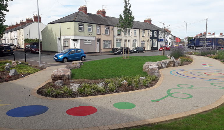 Llun o Albany Street yng Nghasnewydd yn dangos llwybr troed newydd gyda llwybr chwarae lliwgar gyda siapiau a llinellau ar y llawr Llun o Albany Street yng Nghasnewydd yn dangos llwybr troed newydd gyda llwybr chwarae lliwgar gyda siapiau a llinellau ar y llawr