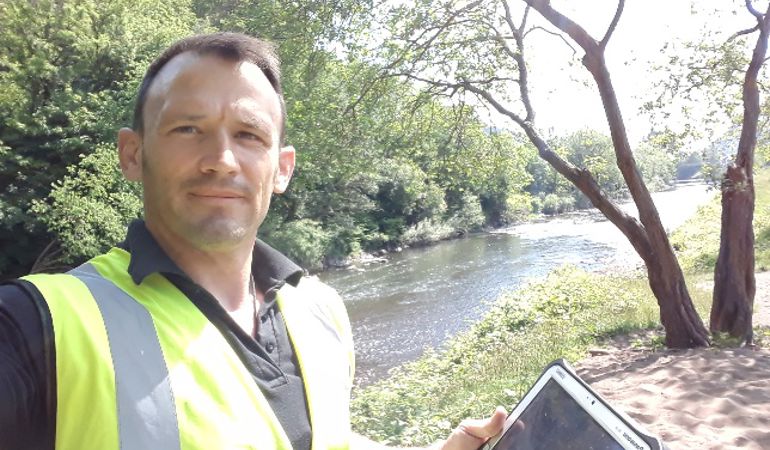 A photo of NRW staff inspecting a river bank for flood damage